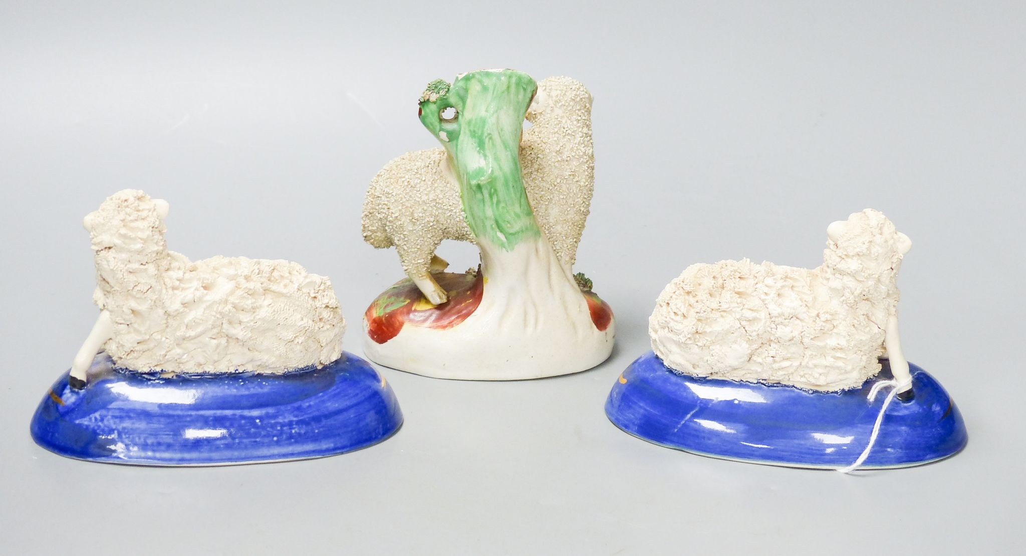 A pair of Staffordshire pottery figures of recumbent sheep, and a similar spell vase, tallest 12.5 cm